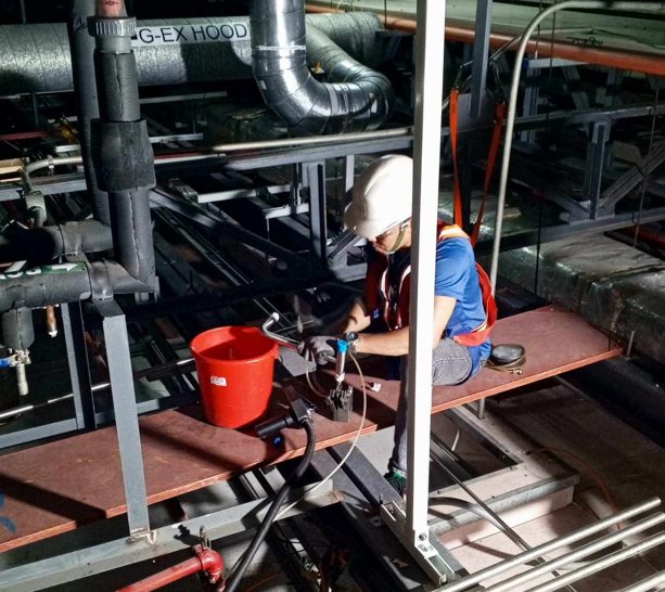 Orbital weld head positioned on stainless gas tubing above the cleanroom plenum