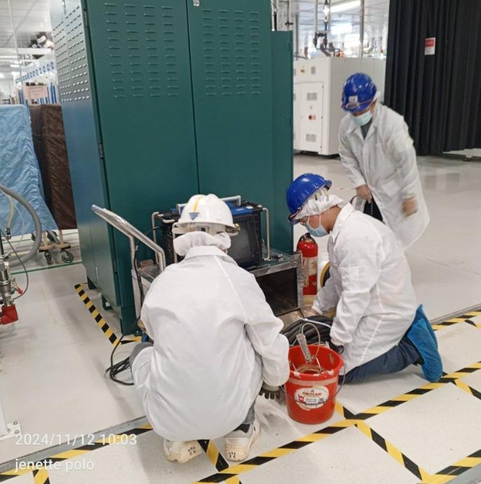 Technician performing orbital welding on tool hook-up tubing in a cleanroom