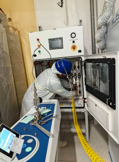 Technician performing helium leak testing on a valve manifold box gas stick