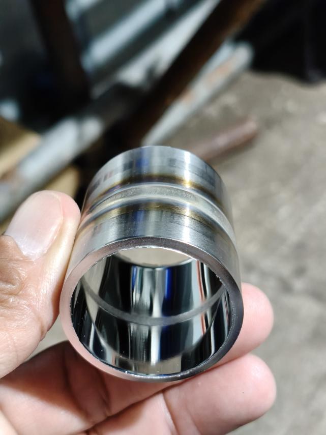 Weld coupon held in the hand, showing the heat-tint bands on the outside and the polished bore inside