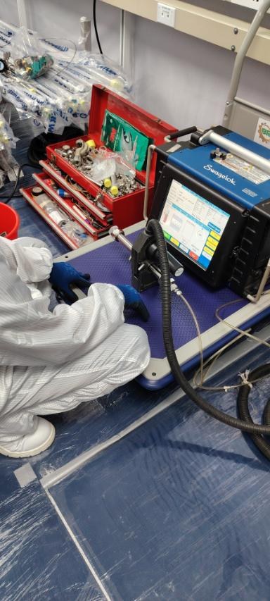 Technician working at an orbital welder control unit inside the cleanroom