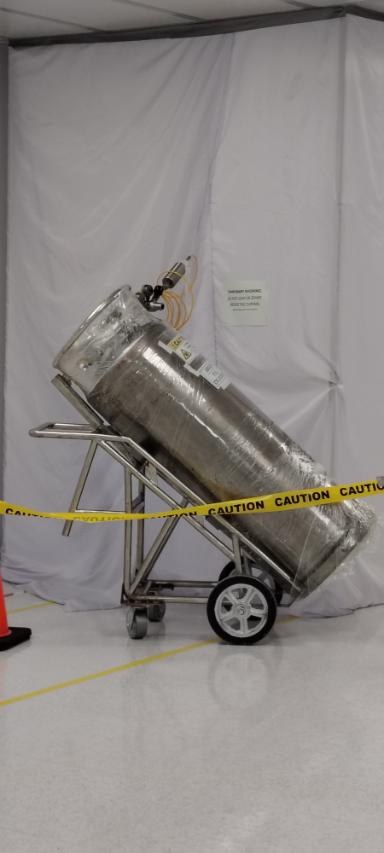 Insulated process vessel staged on a wheeled cart behind caution tape